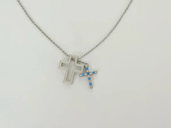 Close view of hypoallergenic double cross pendant: Diamond-encrusted openwork cross + solid blue/clear CZ alternating cross with lobster clasp