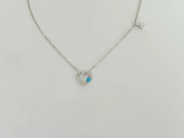 Close-up view of a sterling silver diamond heart necklace: open heart design paved with high-carbon diamonds featuring a turquoise gemstone accent, lobster clasp with diamond charm detail.