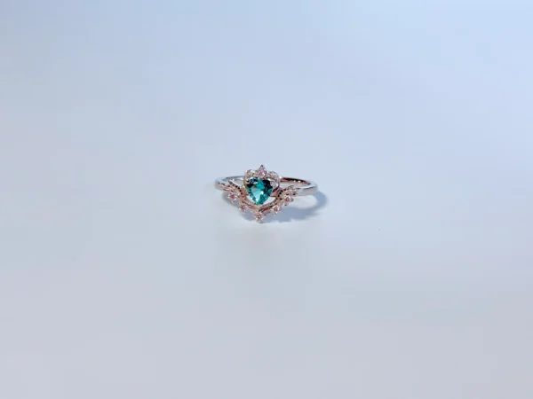 Side profile view of heart-shaped emerald ring showing pavé diamond accents and rhodium-plated sterling silver band.